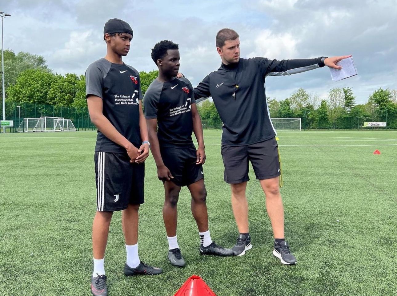 Gerald Latifi coaching young football players on an outdoor pitch